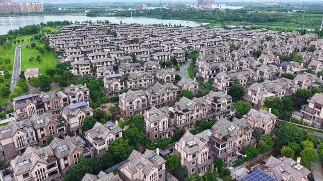 Aerial wide view of dense villa residential community beside lake with lush green trees
