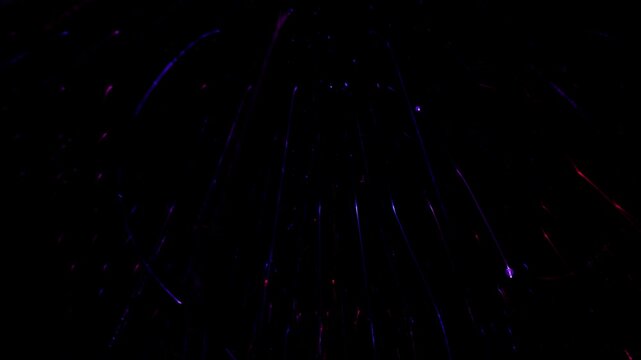 Bright lights move and create patterns in a dark setting during an event at a venue. Colors blend and shift as the lights change. Many people enjoy this display in the evening.