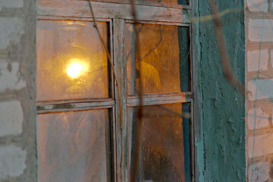 The setting sun is reflected in the window of an old house in Luhansk region, Ukraine