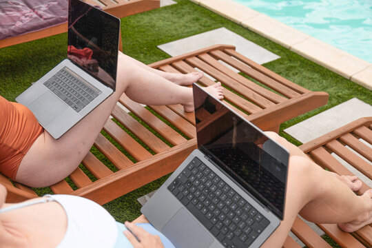 Remote work on laptop while relaxing by a swimming pool