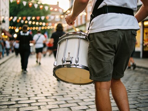 Drummer walking through a festive street parade during a traditional celebration