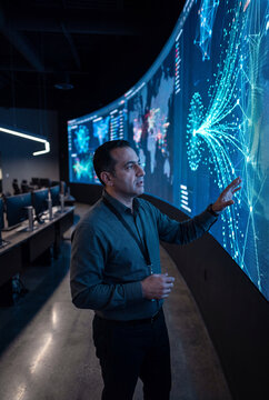Analyst pointing at a curved data wall in a global operations center