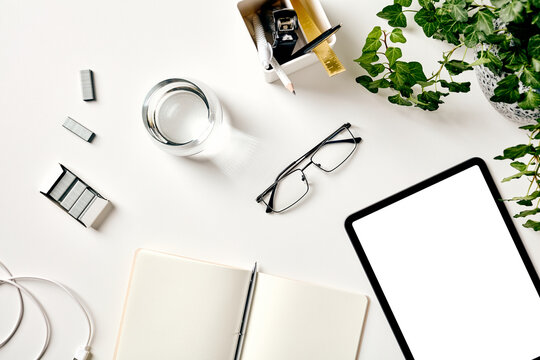 Minimal workspace flat lay with tablet, stationery and plant