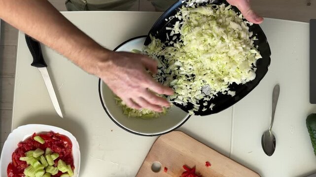 Top-down kitchen scene showing hands assembling fresh cabbage salad in white bowl with tomatoes, cucumber, grated topping, skillet transfer, and cutting prep on countertop