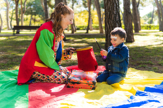 Clown performing magic trick for child on a play parachute