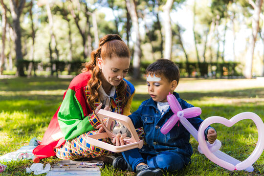 Clown entertaining child with balloon shapes in sunny park