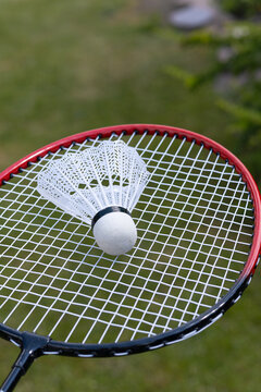 Badminton shuttlecock resting on racket outdoors on court