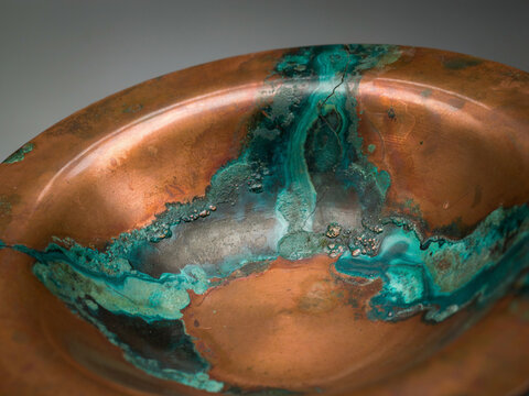 Verdigris patina on copper bowl surface during studio lighting with shallow depth of field abstract texture