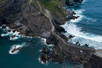 winding pathway along rocky cliffs by ocean waves, aerial perspective of adventure in natural beauty, blue and green tones, stone and concrete materials, travel and outdoor adventure themes. © Angelov
