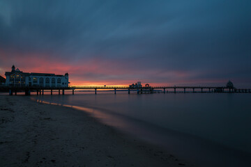Fototapeta premium Wide angle view of Sellin pier extending into tranquil ocean during dark twilight