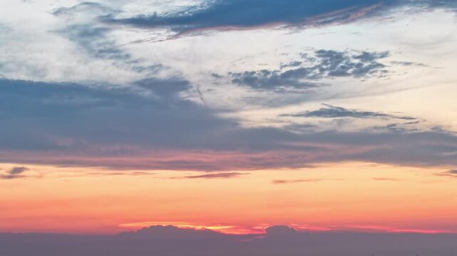 time-lapse，Gradient sunset sky with layered clouds in warm orange and cool blue tones