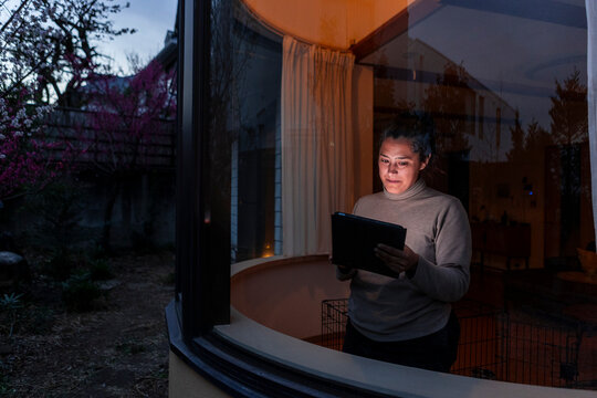 Woman reading on a tablet close to a window