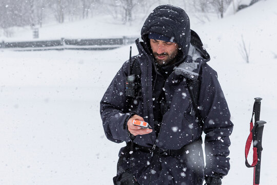 Ski touring man checking avalanche transceiver in powder