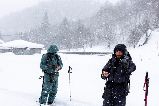 Two men ski touring in Hokkaido powder with beacon safety