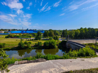 Obraz premium Calm River Landscape With Old Bridge And Lush Foliage Under Sky