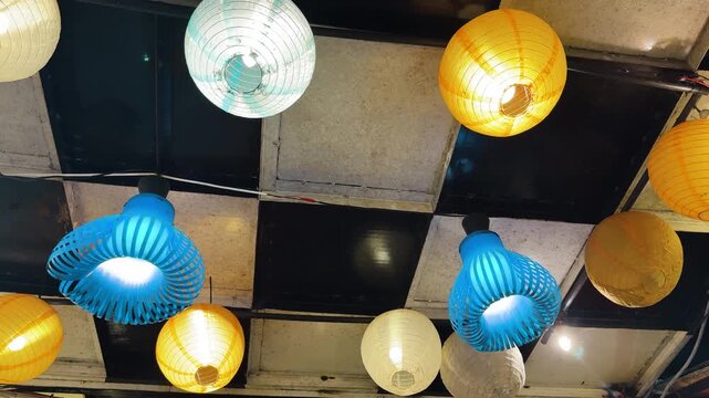 Colorful paper lanterns and unique blue light fixtures hanging on ceiling
