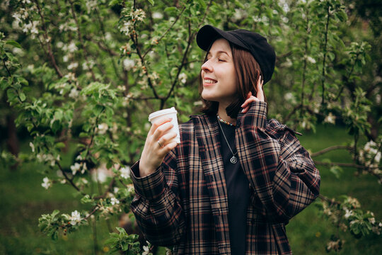 Smiling woman with coffee in spring garden blossom
