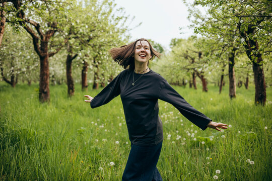 Woman enjoying spring orchard walk among blooming trees