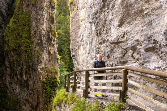 Man hiking through scenic gorge on a wooden path