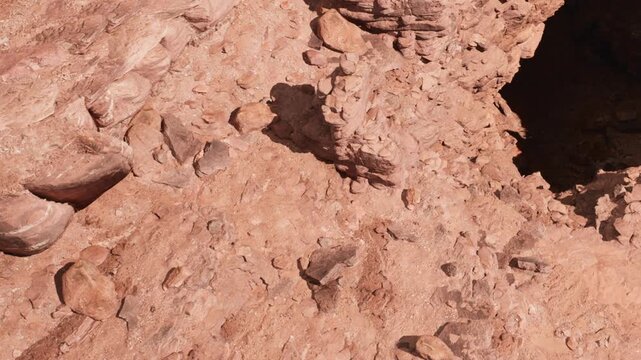 Dinosaur footprints are visible in a rocky area of a desert landscape. The ground is made of reddish earth with the tracks showing clear impressions.