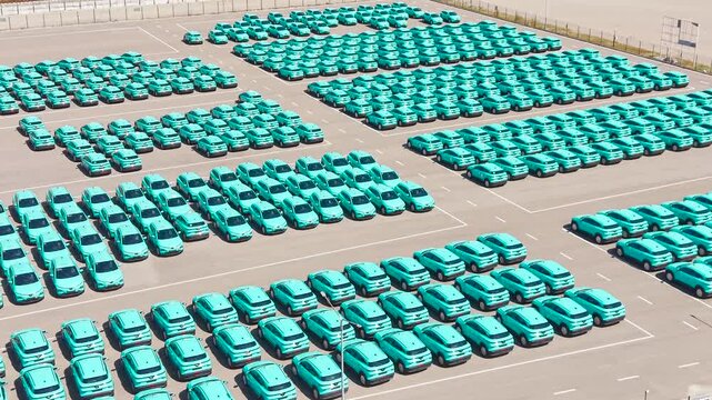 Top view of a parking lot with new turquoise electric crossover taxis.