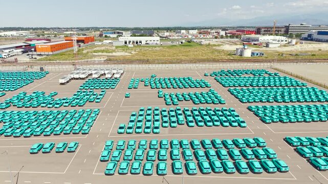 Top view of a parking lot with new turquoise electric crossover taxis.