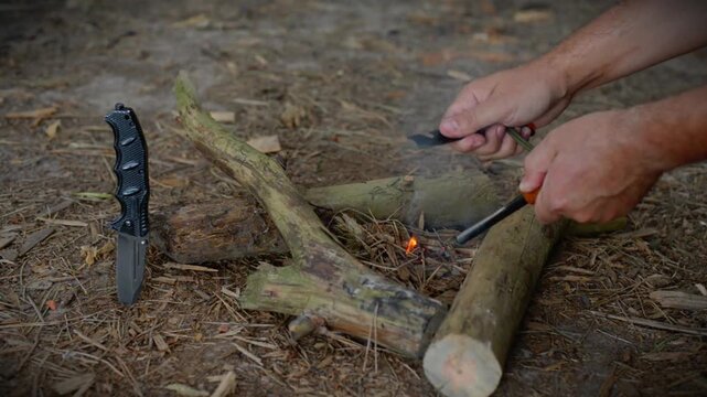 Bushcraft survivalist striking sparks with ferro rod fire striker to light tinder at forest campsite with natural outdoor ambient audio for wilderness survival skills. 