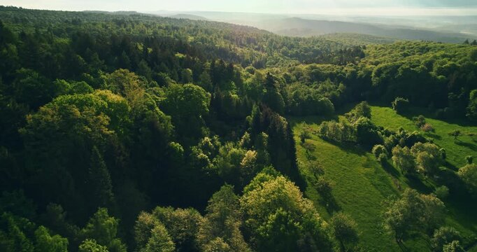 Flying over gorgeous green landscape with deep shades of green in the forests and meadows on hills