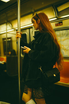 Young woman using smartphone on manhattan subway train