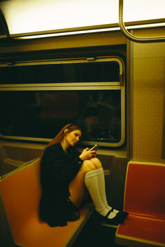 Young woman using smartphone on Manhattan subway at night
