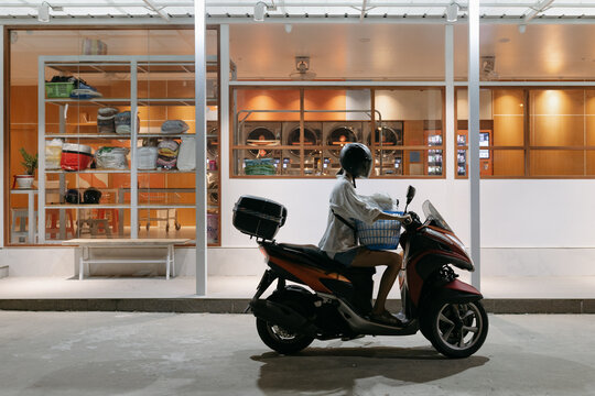 Woman on scooter with laundry basket outside laundromat