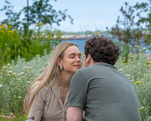 Fototapeta premium Couple sitting and kissing surrounded by nature and plants and sea