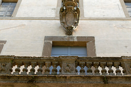 Close-up architectural detail of a stone balcony with balustrades and a carved coat of arms with an eagle on the wall of Villa Mondragone