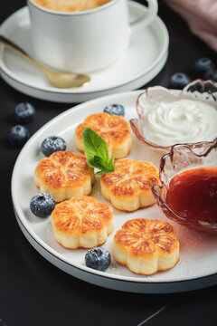 Cottage cheese pancakes, syrniki, curd fritters decorated with strawberry and raspberry served on a white plate. Homemade breakfast concept