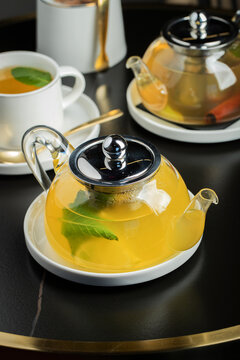 Fruit tea with mango and mint in a glass teapot on the table
