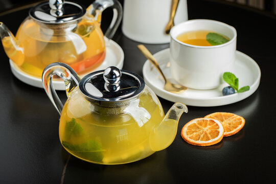 Fruit tea with mango and mint in a glass teapot on the table