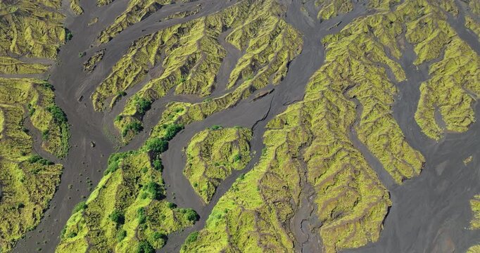 Ambrym Island volcanic terrain showcasing recent black lava fields contrasting with lush green moss and early succession plant growth on ridges and valleys from aerial perspective. Natural background