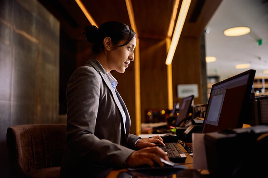 Professional hotel receptionist using computer at front desk.