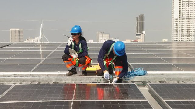 Two solar technicians inspecting rooftop photovoltaic panels, one adjusting panel alignment while colleague points and checks installation details.
