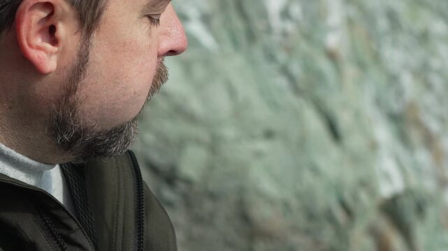 Man eating chocolate bearded guy enjoying a sweet snack bar outdoors in nature against a rocky cliff background