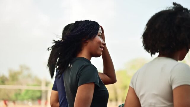 Three young women in sportswear walking and talking together on a stadium track after a workout