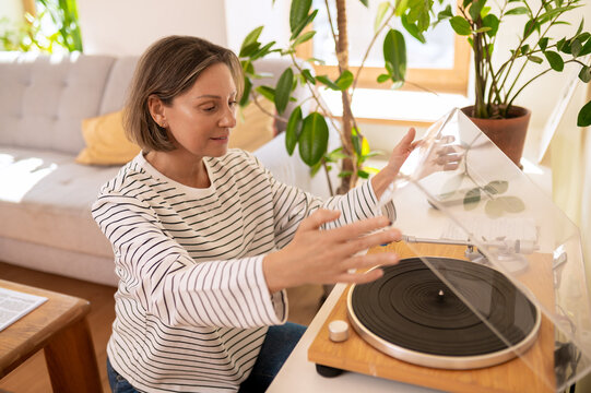 Middle aged woman opening turntable dust cover