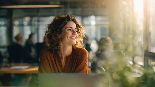 Happy female employee taking a break at a modern office, smiling while looking out the window