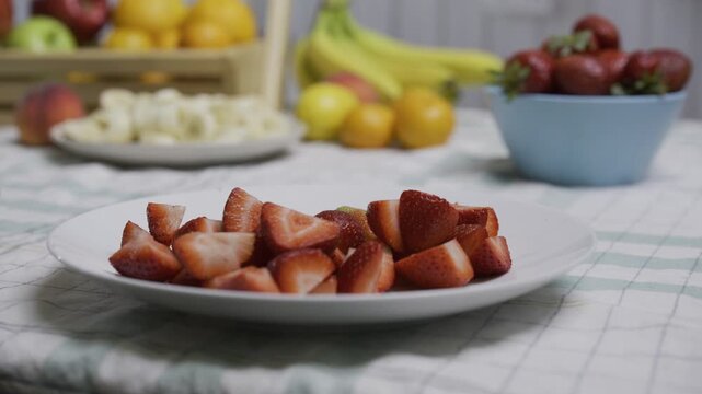 Cut up strawberries being scrapped onto plate - closeup shot