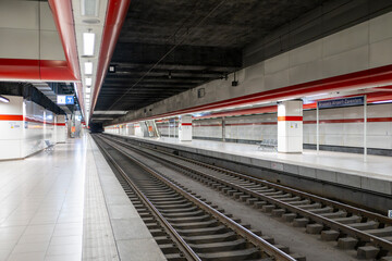 Obraz premium Empty underground railway station platform with parallel train tracks and modern transport infrastructure creating a symmetrical urban transit perspective