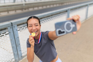 Fototapeta premium Woman celebrating victory biting gold medal taking selfie