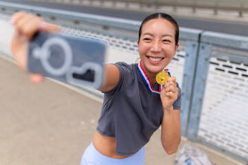 Fototapeta premium Happy female athlete taking selfie with gold medal