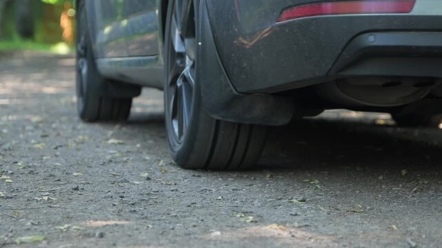 Close-up, view from below the car's wheel, the car starts moving sharply, dust rises from the road