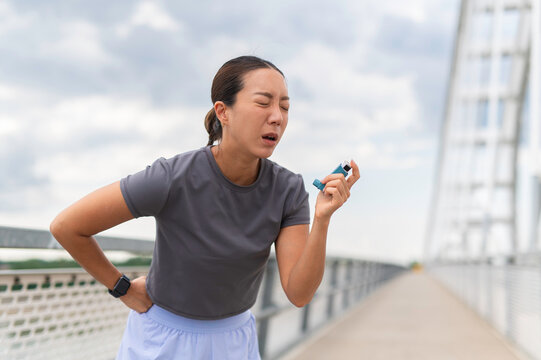 Asian woman suffering asthma attack using inhaler during exercise