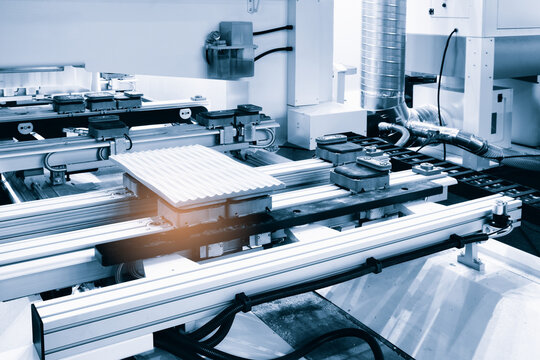 Industrial machine works on sheet of wood. Metal rails support work surface. Control panel and cables are visible.  setup demonstrates precision manufacturing